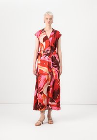 Robe midi florale avec des rouges, des roses et des bruns vibrants ; manches courtes, décolleté en V, taille cintrée avec une ceinture et une jupe fluide.