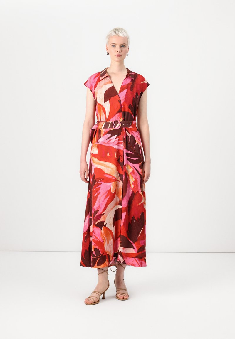 Robe midi florale avec des rouges, des roses et des bruns vibrants ; manches courtes, décolleté en V, taille cintrée avec une ceinture et une jupe fluide.