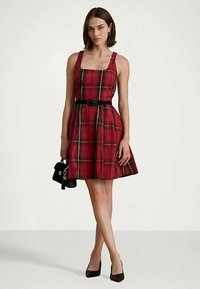 Punane ruuduline kleit nelinurkse kaelusega, istuv kehaosa, flared seeliku ja musta vööga. Mudel kannab väikest musta käekotti, jalas mustad kontsad.