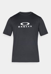 Crna atletska majica s okruglim izrezom, kratkim rukavima i bijelim logotipom "OAKLEY" na prsima. Izrađena je od teksturirane tkanine.