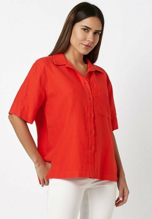 Short-sleeve red button-up shirt with a collar, single chest pocket, and a relaxed fit. Made from lightweight fabric.