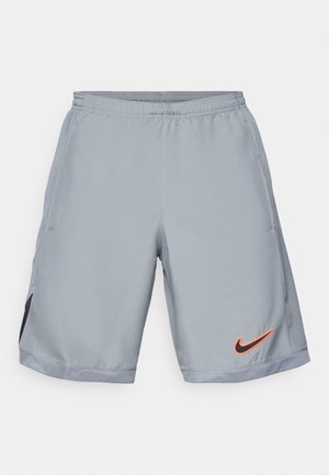 Shorts de sport gris en matériau léger avec une taille élastique. Comprend des panneaux latéraux en mesh noir et un logo Nike orange.