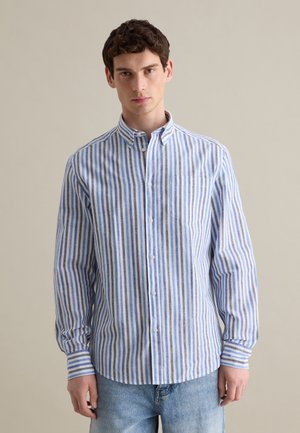 Camisa de botones a rayas azul y blanca con cuello, mangas largas y un bolsillo en el pecho. La tela parece ligera y texturizada.
