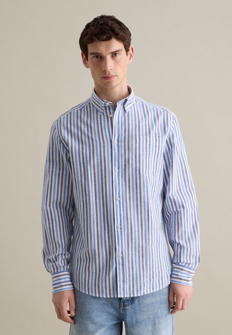 Camicia button-up a righe blu e bianche con colletto, maniche lunghe e taschino sul petto. Il tessuto sembra leggero e di una texture particolare.