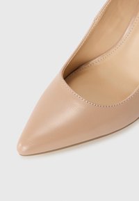 Pantofle nude din piele cu vârf ascuțit și un design cu decupaj. Textură netedă și estetică minimalistă.