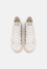 White and gray sneakers featuring a canvas upper, rubber sole, and textured side panels. Classic lace-up design with branded detail.