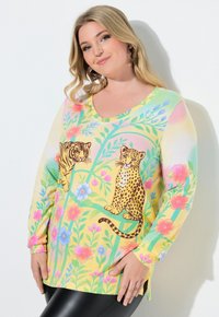Bluzka z długim rękawem i dekoltem w serek w pastelowożółtym kolorze, ozdobiona nadrukami tygrysów i lampartów oraz wzorami kwiatowymi. Miękka tkanina z bocznymi rozcięciami przy dolnym brzegu.