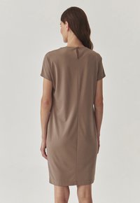 Pruun lühikeste varrukate ja lõdva istuvusega kleit, millel on tagasi peen keyhole detail ja sile tekstuur. Keskmise reie pikkus.