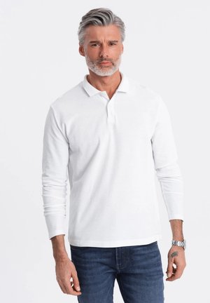 Witte lange mouwen polo shirt van katoen met een klassieke kraag, gecombineerd met blauwe denim jeans. De pasvorm is ontspannen, met een gladde textuur.