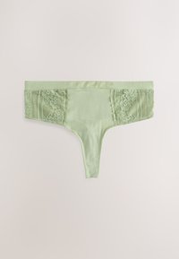 Tanga vert clair avec un corps en tissu doux. Les panneaux en dentelle sur les côtés présentent des motifs floraux et des accents en maille, offrant un design délicat.