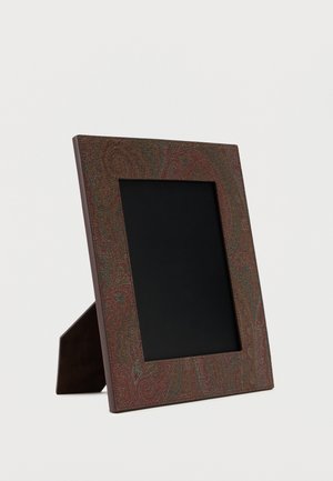 Marco de foto decorativo rectangular con borde marrón de patrón cachemira, colocado verticalmente con un área de exhibición negra y un soporte trasero marrón.