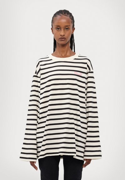 Camisa de manga longa às riscas em creme e preto com mangas largas, decote redondo e pequeno logotipo vermelho no peito. Tecido de algodão macio.