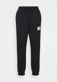 Schwarze Jogginghosen aus weichem Stoff, mit einem elastischen Bund mit Kordelzug, Bündchen an den Knöcheln und einem kleinen weißen Logo-Patch.