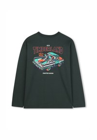 Chemise à manches longues vert foncé avec un graphique d'un pick-up transportant des bottes, "Timberland 1973," et le texte "Crafted Goods" au dos.