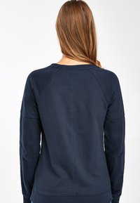 Sweatshirt bleu marine à manches longues avec un col rond et des manches raglan, fabriqué en coton, avec une texture lisse et un design simple.