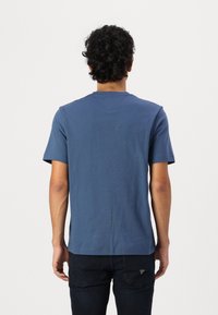 Blå bomullströja med korta ärmar, rund halsringning och en avslappnad passform. Har en slät yta, minimala detaljer och en rak fåll.