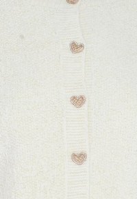 Weißer Cardigan aus strukturiertem Material mit gerippten Details und herzförmigen Knöpfen mit funkelndem Finish.