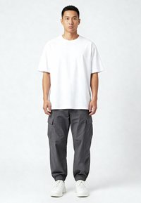 Valge puuvillane T-särk, lõtva lõikega, koos hallide cargo-pükstega, millel on küljetaskud, elastsed mansetid ja valged tossud. Lihtne, juhuslik riietus.