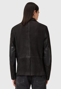 Chaqueta de cuero en marrón oscuro con un acabado suave, con parches de cuero negro en los codos, corte ajustado y puños con botones.