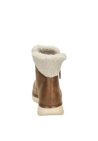 Stivale alla caviglia in pelle marrone con risvolto in pelliccia sintetica crema, collo arrotondato e suola in gomma. Presenta una texture liscia con accenti di design minimal.