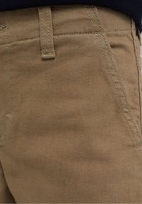 Khaki byxor gjorda av texturerat tyg, med stickade sömmar, en framficka och en standard midjebandsdesign.