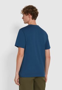 Maglietta in cotone blu navy con collo rotondo e maniche corte, caratterizzata da una texture semplice e una vestibilità rilassata, vista da dietro.