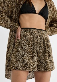 Bermudy s leopardím vzorem s elastickým pasem, s bočními kapsami a volnějším střihem. Materiál je lehký a texturovaný.