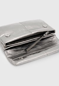 Clutch metallizzato argento con una texture liscia, tasca interna con zip e due chiusure a scatto. Presenta un design elegante e hardware minimale.