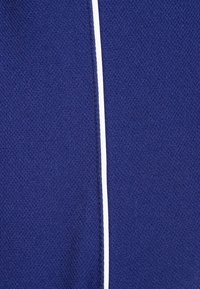 Granatowa tkanina o fakturowanej powierzchni, z białym pionowym paskiem na środku, wskazującym na sportowy element designu.