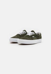 Zapatillas de ante verdes con cordones blancos y suelas de goma. Presentan un diseño clásico de corte bajo y un pequeño logo en el lateral.