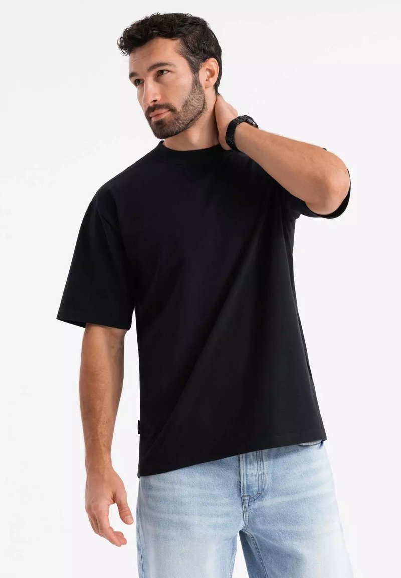 Černé tričko s krátkým rukávem a volným střihem, vyrobené z bavlny, s kruhovým výstřihem a decentním designem. Bez viditelných vzorů nebo akcentů.