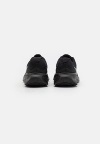 Schwarze Sportschuhe mit strukturiertem Obermaterial und gepolstertem Sole, ausgestattet mit einer runden Ferse und Gummisohle für besseren Halt. Kein sichtbares Logo.