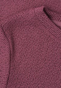 Close-up of a textured mauve knit sweater showing detailed woven pattern and ribbed neckline.