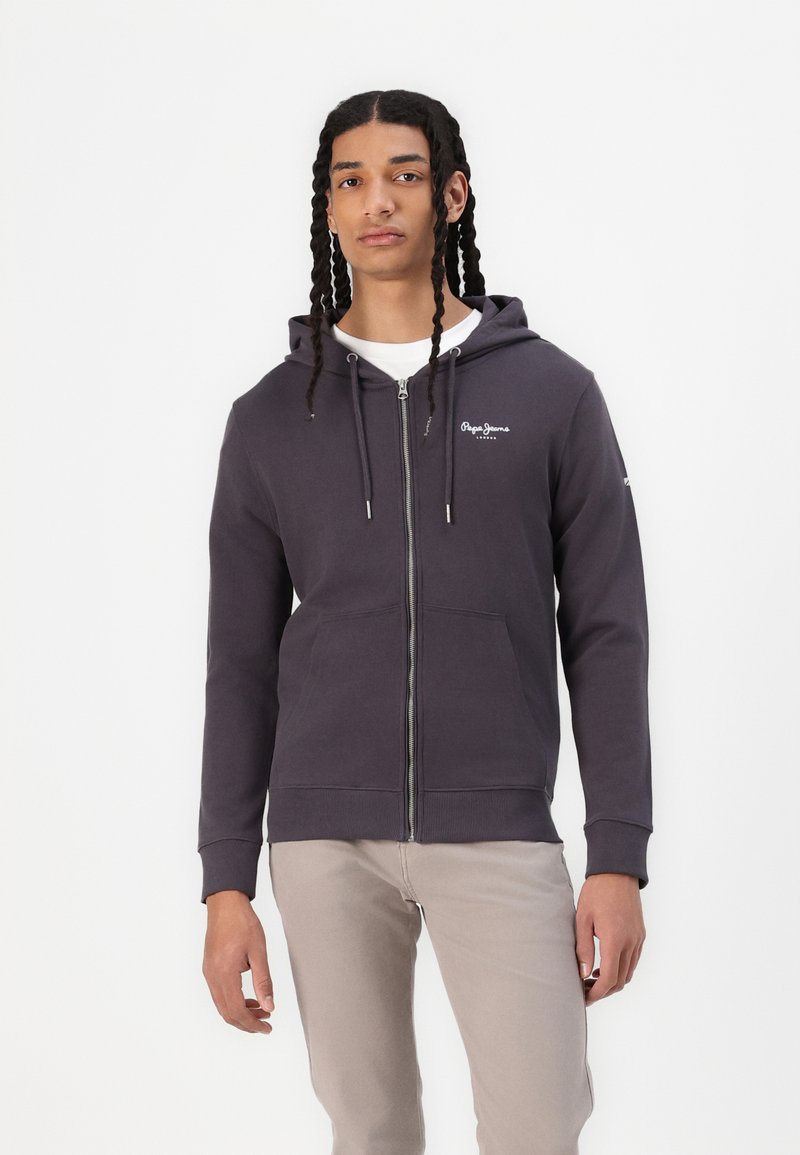 Sudadera con cremallera de color gris oscuro hecha de un tejido suave, que cuenta con capucha, bolsillos frontales y un logo blanco en el lado izquierdo del pecho.