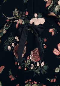 Donkere stof met een bloempatroon van roze en groene bloemen. Inclusief een zwarte stoffen strik op de taille en een gladde textuur.