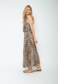 Maxikleid mit Leopardenmuster, Rundhalsausschnitt, fließendem Stoff und lockerer Passform. Kombiniert mit leichten, schnallen Sandalen.