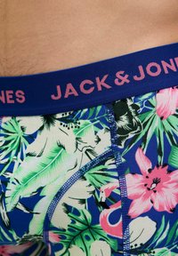 Blaue, mit Blumenmuster versehene Boxershorts mit einem elastischen Bund in Pink und Blau, auf dem der Markenname "JACK & JONES" prangt. Das Muster umfasst tropische Pflanzen und Blumen.