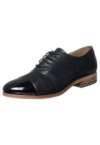 Chaussure Oxford en cuir noir avec un bout en cuir verni brillant, fermeture à lacets et petit talon empilé. Partie supérieure texturée avec des accents lisses.