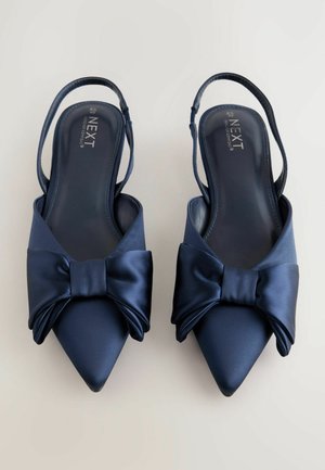 Navy satin slingback shoes with a pointed toe, featuring a large bow accent across the front and an adjustable strap.