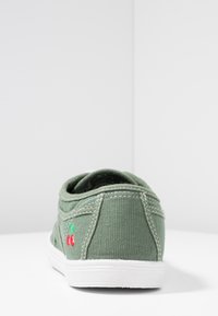 Sneaker in tela verde con suola bianca, caratterizzata da ricami di ciliegie rosse e verdi sul lato e dettagli cuciti lungo il retro.