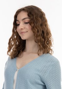 Világoskék kötött kardigán V-nyakkal és gombos záródással, texturált mintával és hosszú ujjal.