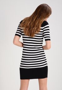 Lyhythihainen mekko, jossa on vaakasuorat mustavalkoiset raidat, istuva malli, resorikangas ja yksivärinen musta helma.