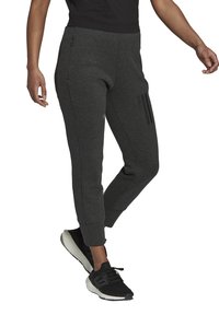 Grau Sweathosen aus weichem Material, mit slim Fit, seitlichen Taschen und drei horizontalen schwarzen Streifen auf dem linken Oberschenkel.