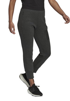 Grijze joggingsbroek van zacht materiaal, met een slim fit, zijzakken, en drie horizontale zwarte strepen op de linker bovenbeen.