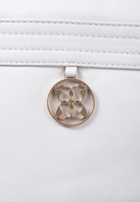 White leather bag featuring a textured surface, vertical seams, and a circular gold hardware accent with an intricate design.