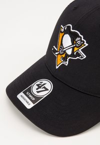 Schwarze Baseballmütze mit gesticktem Pinguinlogo und gelben Akzenten. Verstellbarer Riemen mit einem Etikett "47 MVP." Glatte Textur.