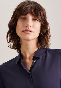 Marineblauwe, short-sleeve shirt met een kraag en knoopdetails. Glad stof met een subtiele glans, geen zichtbare patronen of accenten.