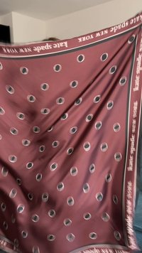 Vinröd halsduk med prickigt mönster i svart och vitt. Kantad med en smal beige kant, tryckt med varumärkesnamn i vitt.