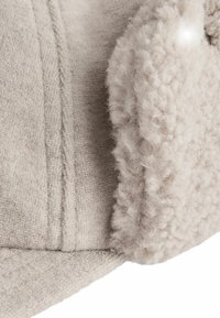 Lys beige fuzzy fleece-stof med blød, tekstureret overflade; har en plys.krave og subtile syede linjer som designdetalje.