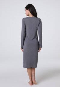 Nightgown grigia a maniche lunghe con taglio dritto, tessuto morbido e dettagli in pizzo sui polsini. Cade fino alla metà del polpaccio.